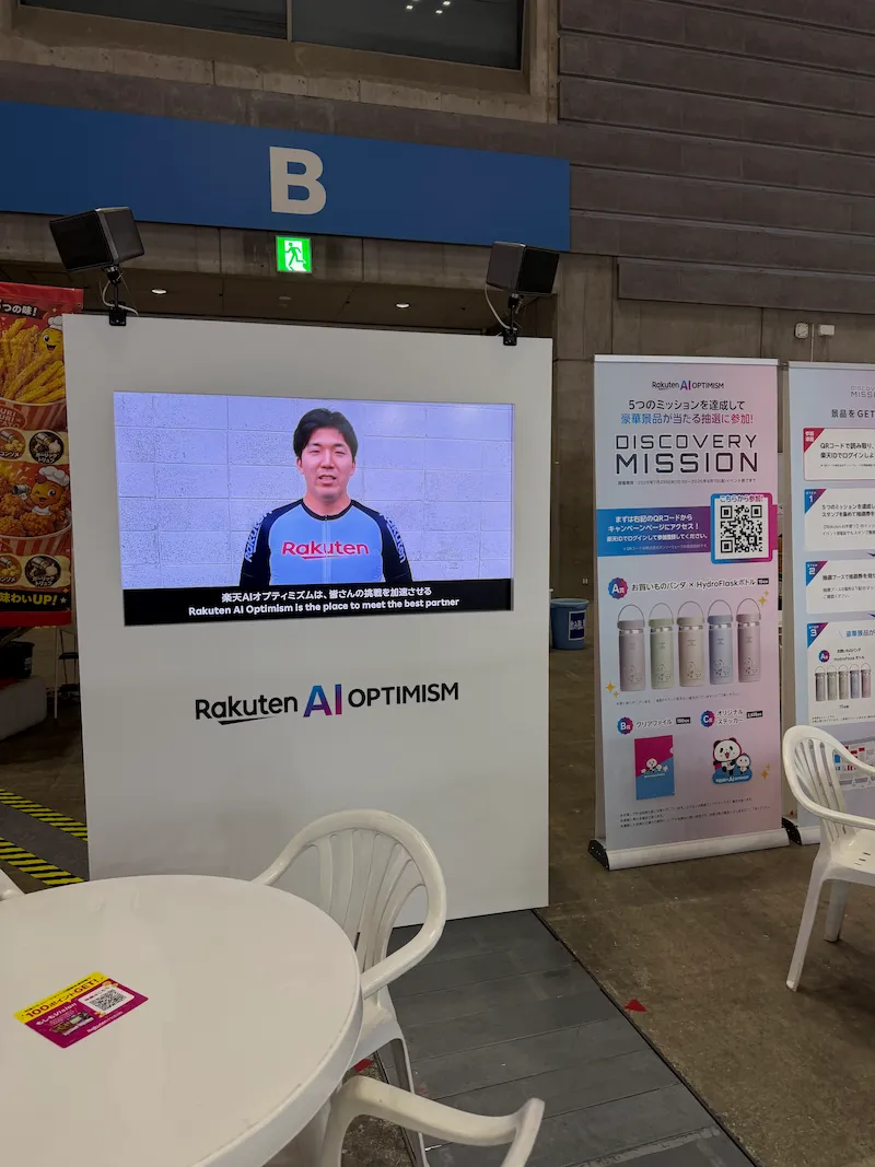 楽天モバイル AI Optimism会場の申込ブース案内スクリーンとキャンペーンバナー
